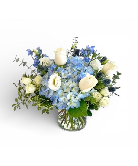 Blue and white hydrangea and more in a clear glass vase