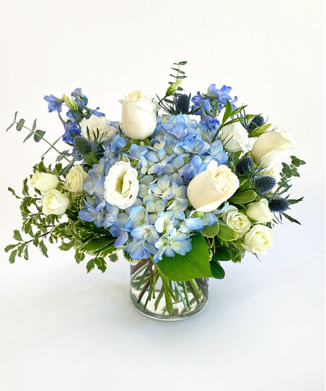 Blue and white hydrangea and more in a clear glass vase