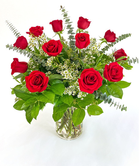 One dozen red roses and foliage in a clear glass vase
