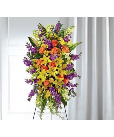 Sympathy spray of pastel flowers presented on a standing easel
