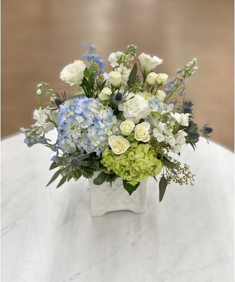 White and blue blooms arranged in a keesake white ceramic container
