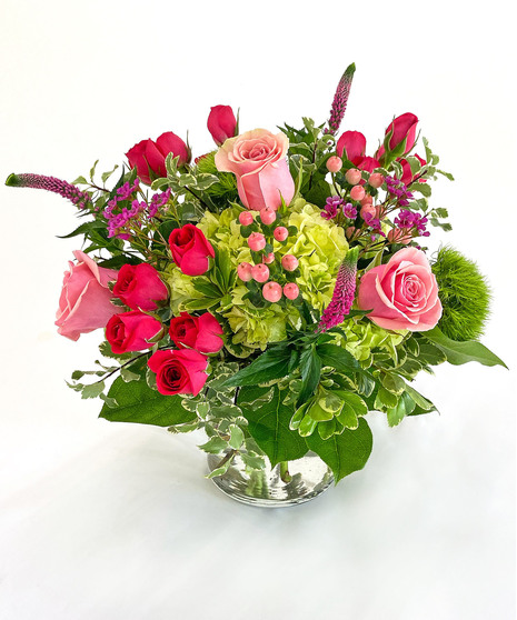 Petite collection of high end flowers in pinks and greens in a clear glass vase